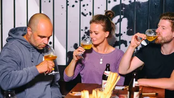 Drei Personen genießen Bier in einem modernen Restaurant.